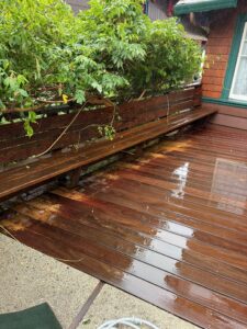 A wooden bench and the surrounding deck area, both bright and clean after receiving professional pressure washing services by Spotfree Window.