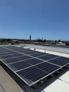 A wide shot of a commercial solar panel array on a flat commercial roof in an urban area, cleaned by Spotfree Window to maximize solar efficiency.