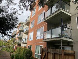 A commercial apartment complex with orange stucco facades and glass balconies, demonstrating the scale of commercial window cleaning services by Spotfree Window.