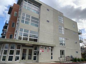 Exterior view of a multi-story gray commercial apartment building with large windows ready for or after professional cleaning by Spotfree Window.