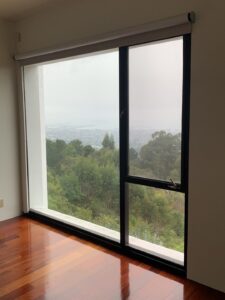 A crystal-clear large window inside a commercial or apartment building after a professional window cleaning by Spotfree Window, featuring a scenic foggy landscape and polished wood floors.