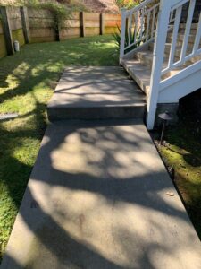 A concrete backyard walkway and steps with dirt buildup, ready for professional pressure washing by Spotfree Window.