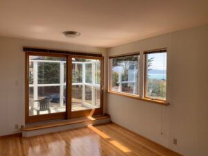 A bright, sunlit living room with clean, spot-free windows looking out to the ocean, demonstrating the impact of professional residential window washing.