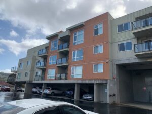 A wide view of a commercial apartment building featuring red/orange and green sections, showcasing the need for professional window cleaning services.