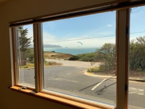 A crystal-clear residential window offering an unobstructed view of the ocean and a paraglider, thanks to a professional window cleaning by Spotfree Window.