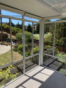 A clean sunroom with large windows offering a clear, streak-free view of a lush garden after a residential window cleaning by Spotfree Window.
