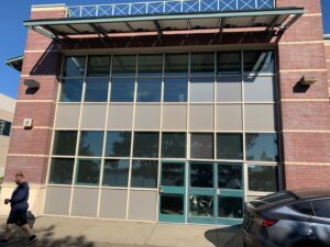 A brick building with a large grid of storefront windows and a blue door, kept clean by Spotfree Window's professional business window cleaning service.