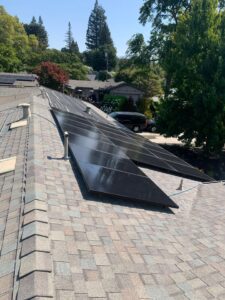 A residential home with dark solar panels on a gray shingle roof, professionally cleaned by Spotfree Window to boost home energy savings.
