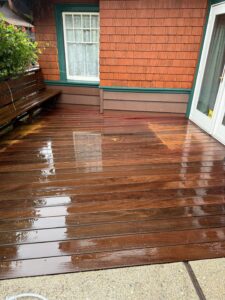 A close-up of a freshly pressure washed wood deck with a rich, wet sheen and visible grain pattern.