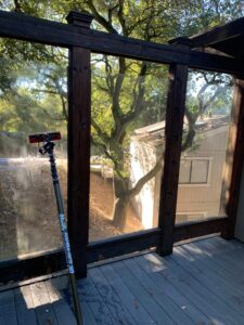 A water-fed pole being used to clean a glass railing and adjacent windows as part of a complete whole house washing service.