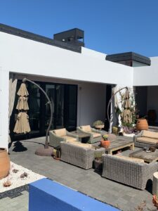 A clean, modern white home with a spacious outdoor patio, wicker furniture, and glass doors after a full whole house washing by Spotfree Window.