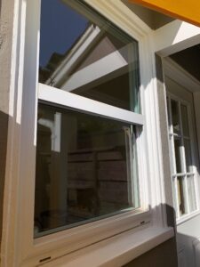 A close-up detail shot of a clean white window frame and streak-free glass after a professional residential window washing service.