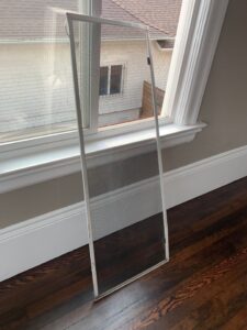 A window screen removed and leaning against the wall, part of the detailed preparation process for professional residential window washing.