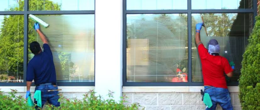 Professional window cleaners washing a commercial storefront to improve business curb appeal and retail foot traffic.